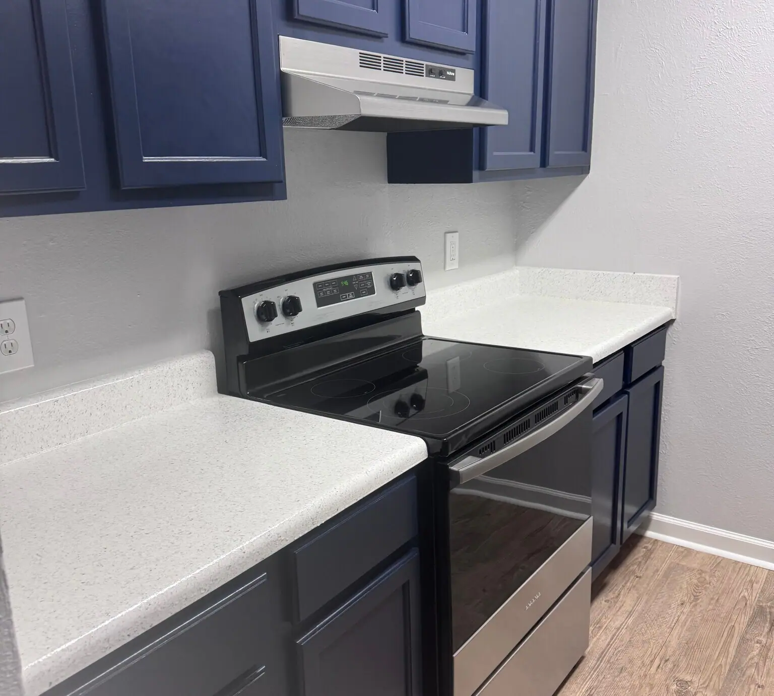 A Cypress Cove apartment kitchen with blue cabinetry, light counters, and stainless appliances